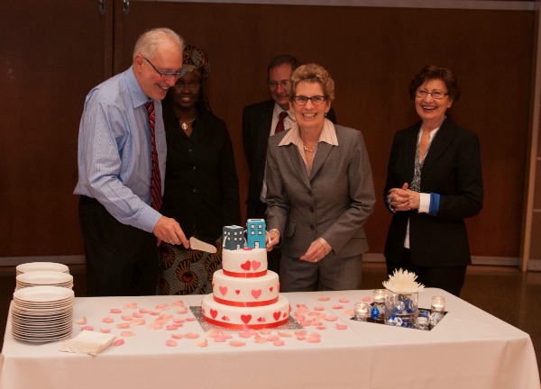Premier of Ontario, Kathleen Wynne, cutting the wedding cake with Ryerson University President, Sheldon Levy, at the Social Planning Toronto symposium with a marriage/wedding theme. Photography by Jeremy Tudor Price